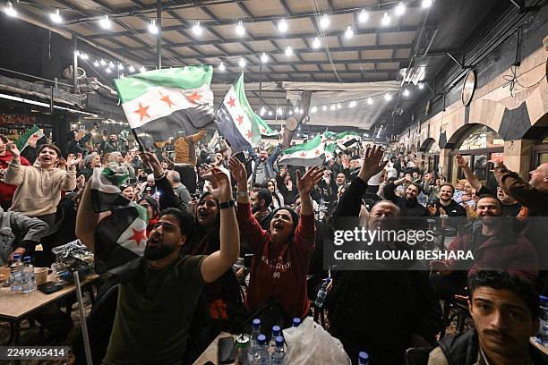 Syrians celebrate at a cafe in the Syrian capital Damascus on December 7 after their national team's match against Palestine ended in a 0-0 draw in...
