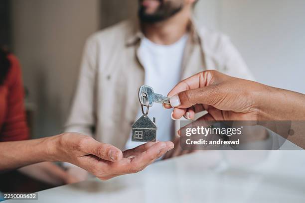 coppia felice che riceve nuove chiavi di casa dall'agente immobiliare - casa in affitto foto e immagini stock