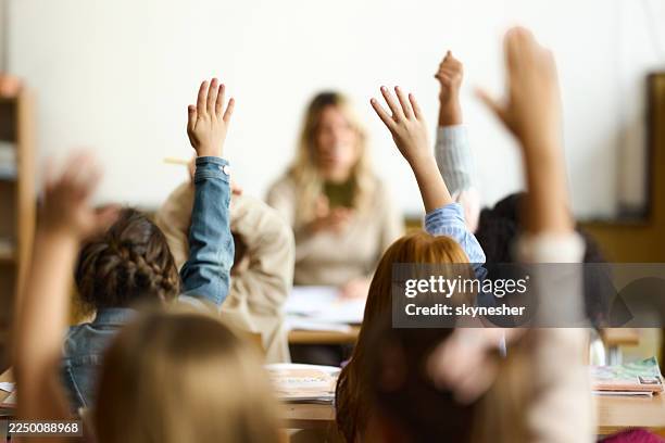 back view of elementary students know the answer on a class. - handen in de lucht stockfoto's en -beelden