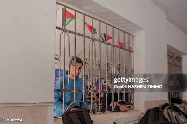 Two students stand behind a barred window inside a classroom at Al-Azhar University in Gaza City, Palestine, on December 7, 2025. After two years of...
