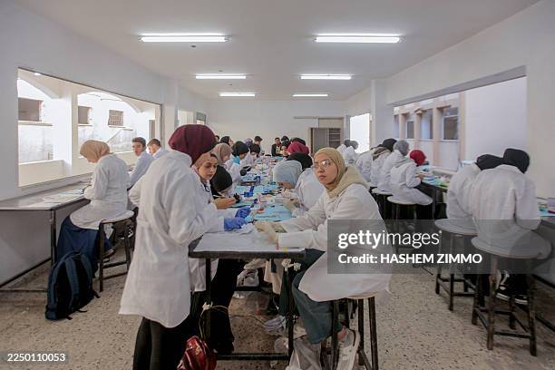 Students wearing lab coats gather around a workbench during a dentistry session at Al-Azhar University in Gaza City, Palestine, on December 7, 2025....