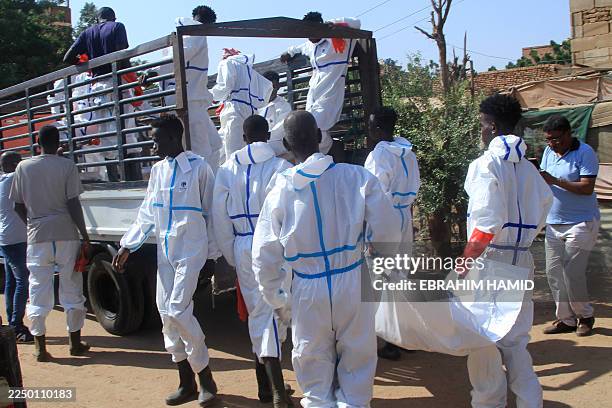 Employees working for the authorities load a body bag into the back of a lorry as bodies are dug up from an emergency burial site inside a school, to...