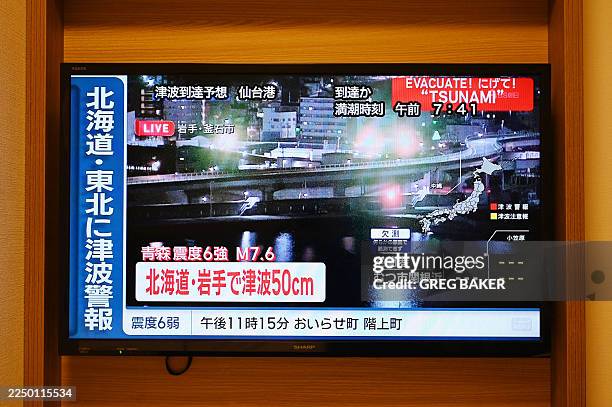 Tsunami warning flashes over live footage of a waterfront area, on a television screen in Sapporo, in Japan's northern Hokkaido prefecture on...