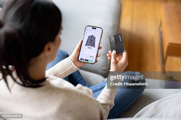 woman at home buying clothes online using a mobile app and paying by credit card - home shopping stock pictures, royalty-free photos & images