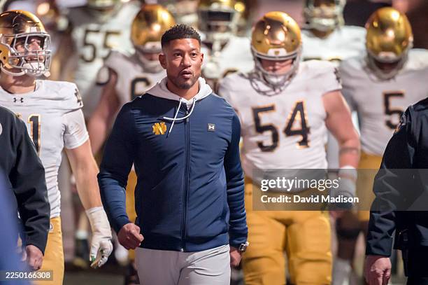 Head Coach Marcus Freeman of the Notre Dame Fighting Irish leads his team into the stadium to start the second half of a college football game...