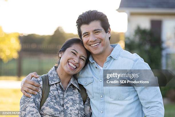 joyful military woman reunites with her supportive partner outdoors during golden hour. - welcome home stock pictures, royalty-free photos & images
