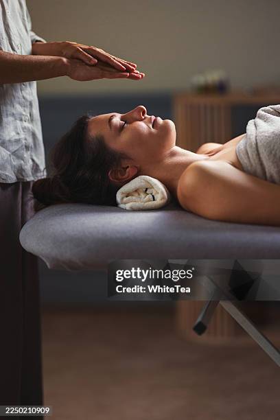 sesión de masaje relajante en el spa con terapeuta que calma al cliente en la mesa bajo luz cálida - reiki fotografías e imágenes de stock