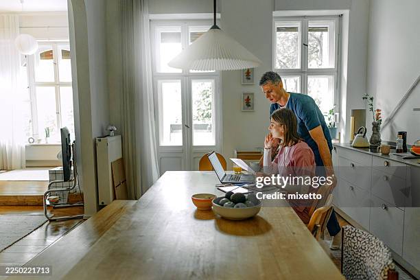couple in medical scrubs using laptop in a domestic kitchen at home - distant stock pictures, royalty-free photos & images