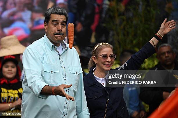 Venezuela's President Nicolas Maduro tosses a carrot into the air upon his arrival with First Lady Cilia Flores at a rally marking the anniversary of...