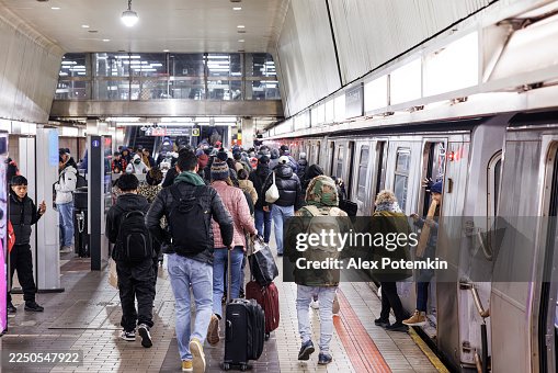 Busy subway platform in Queens, NYC with a crowd of people boarding a train during rush hour. Busy subway platform in Queens, NYC with a crowd of people boarding a train during rush hour.