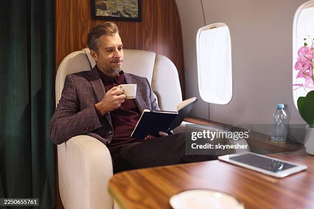 smiling businessman reading his plans in a private airplane. - billionaire stock pictures, royalty-free photos & images