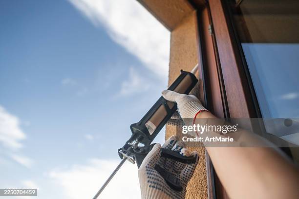 man using sealant caulk to repair window - caulk gun stock pictures, royalty-free photos & images