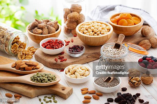 frutas secas, frutos secos y bayas sobre la mesa de la cocina. comida o tentempié saludable y fresco rico en fibra, ideal para el cuidado del sistema digestivo o para la pérdida de peso, el bienestar y la nutrición - fruta seca fotografías e imágenes de stock