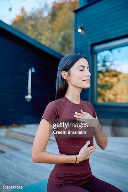 woman meditating outdoors practicing deep breathing exercises - spiritual enlightenment stock pictures, royalty-free photos & images