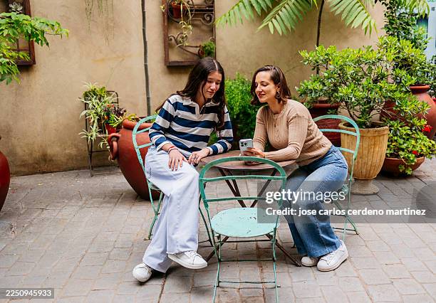 mother and daughter using smartphone at cafe courtyard - generation gap stock pictures, royalty-free photos & images