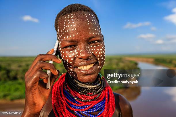 jeune fille de la tribu de karo utilisant un téléphone intelligent, ethiopie, afrique - peinture corporelle photos et images de collection