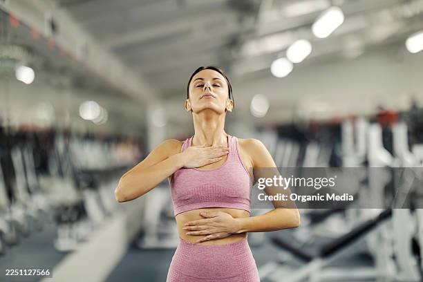 woman practicing deep breathing exercise for calm mind at gym - belly breathing stock pictures, royalty-free photos & images