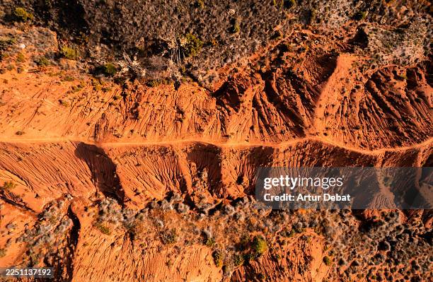 directly overhead view of a trail on a rugged eroded pattern with red earth colors - narrow path stock pictures, royalty-free photos & images