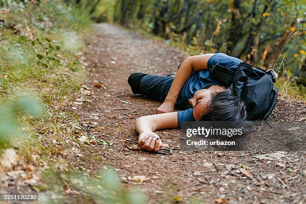 unconscious injured female hiker lying on the ground in the mountain - unconscious stock pictures, royalty-free photos & images