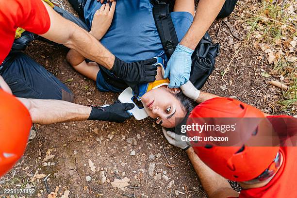 mountain rescuers putting a neck brace on an unconscious injured female hiker on the mountain - unconscious stock pictures, royalty-free photos & images
