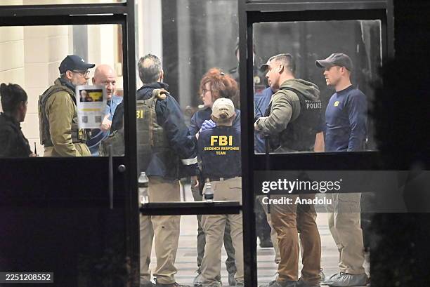 Members of the FBI Evidence Response Team work at the scene near a body, collect evidence and mark the area with evidence markers at Brown University...