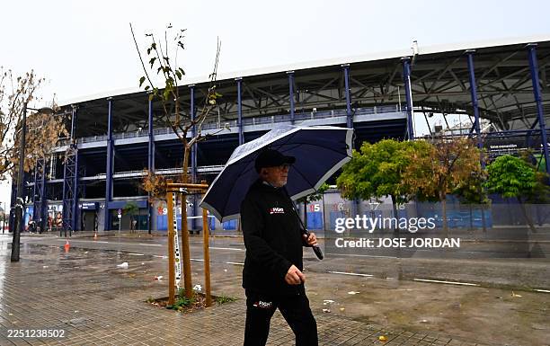 Man walks with an umbrella outside the Ciutat de Valencia stadium after the Spanish league football match between Levante UD and Villarreal CF was...