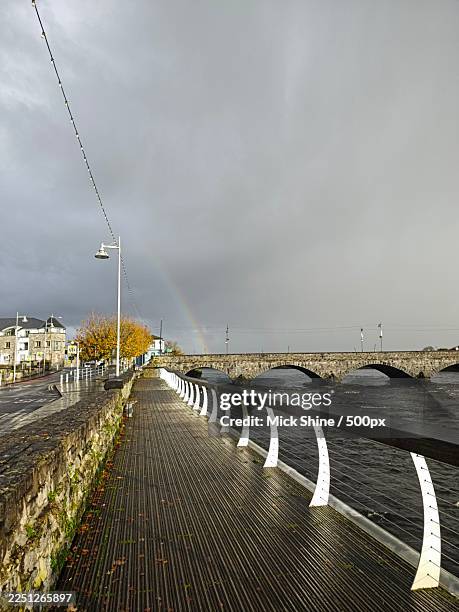 rainbow over a stone bridge and river with a boardwalk and street on a cloudy day,limerick,ireland,limerick city - verwaltungsbezirk county limerick stock-fotos und bilder