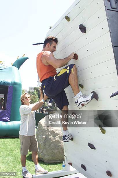 S Trevor Goddard tries his luck on a rock climbing wall at the premiere of Discovery Channel's 'When Dinosaurs Roamed America' at the Bing Theater...