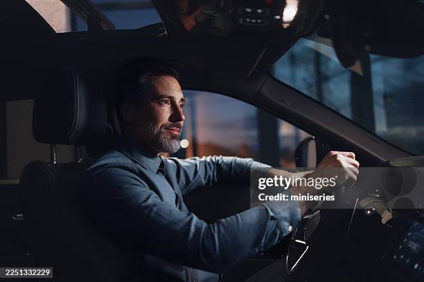 professional businessman driving a car at night in a modern vehicle for corporate travel - interior de carro imagens e fotografias de stock