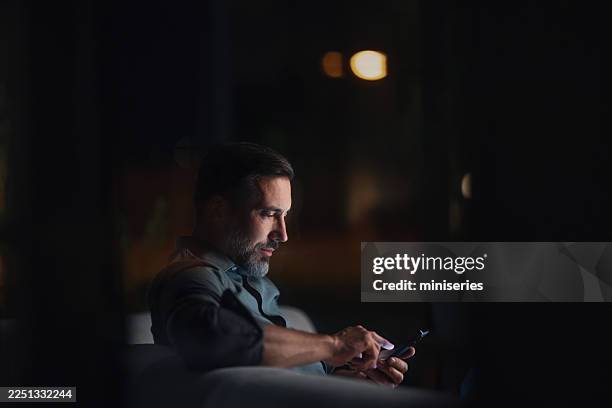 empresario enfocado usando su smartphone por la noche en una oficina moderna y oscura - penumbra fotografías e imágenes de stock