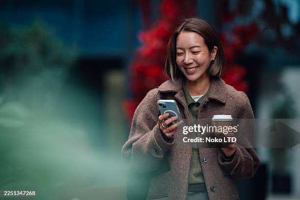 junge erwachsene frau genießt kaffee und schaut aufs handy - bob frisur stock-fotos und bilder