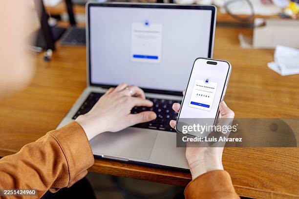 secure login process with woman entering two factor authentication verification code from phone to laptop - verification stock pictures, royalty-free photos & images