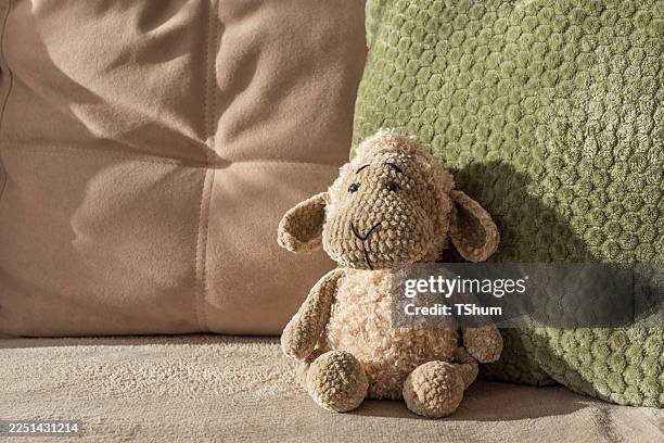 Knitted Plush Sheep on Beige Couch with Cushions in Natural Sun Light