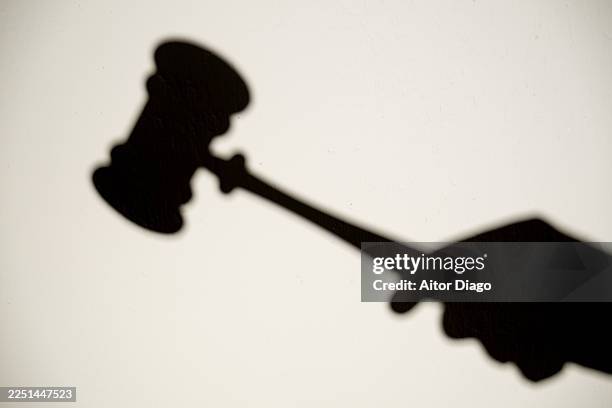 shadow on a wall of judge hitting gavel in court, concept of justice, law, and legal protection - regeln stock-fotos und bilder