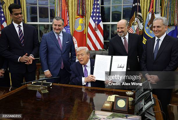 President Donald Trump displays a signed executive order as U.S. Sen. Ted Cruz , Commerce Secretary Howard Lutnick and White House artificial...