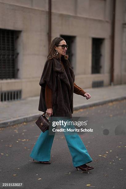 Annette Weber is seen wearing a dark brown faux mink fur jacket with a plush, short sleeves, wide draped lapels and a relaxed cape like silhouette...