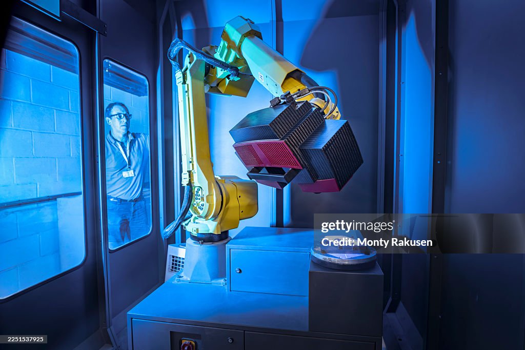 Operator watching robot scanning finished parts for quality control in aerospace parts factory