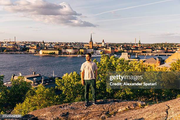 man looking at stockholm skyline from the cliff in summer, sweden - riddarholmen stock-fotos und bilder
