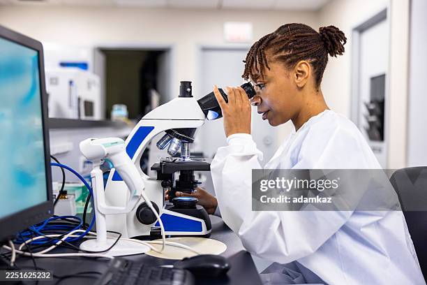 tecnico di laboratorio donna nera che analizza campioni al microscopio in un laboratorio ospedaliero - laboratorio medico foto e immagini stock