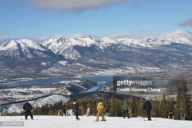 Snowboarders and skiers look down Lake Dillon and Silverthorne from the summit at Keystone ski resort in Colorado on Tuesday, December 16, 2025.