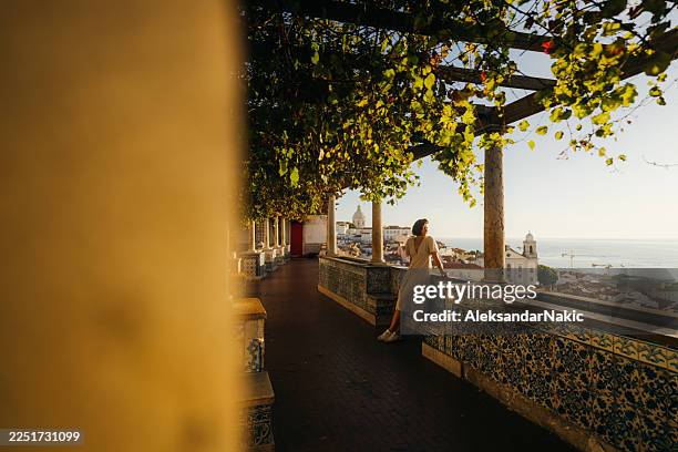 female tourist enjoys the skyline and horizon over of the city of lisbon, portugal - lissabon stockfoto's en -beelden