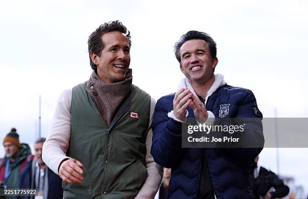 Ryan Reynolds, Co-Owner of Wrexham, and Robert McElhenney, Co-Owner of Wrexham, interact as they walk around the pitch prior to the Sky Bet...