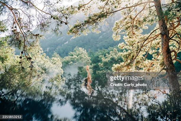 a woman stretches her arms toward the sky amid a misty, sunlit forest. - beauty in nature stock pictures, royalty-free photos & images