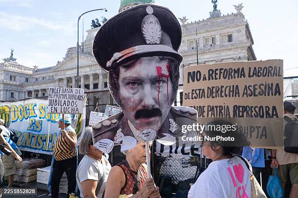 Retired elderly woman carries a sign with the image of Javier Milei dressed as dictator Jorge Rafael Videla in front of the Capitol in Buenos Aires,...