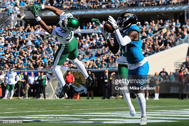Brian Thomas Jr. #7 of the Jacksonville Jaguars makes a catch for a touchdown defended by Qwan'Tez Stiggers of the New York Jets during the first...
