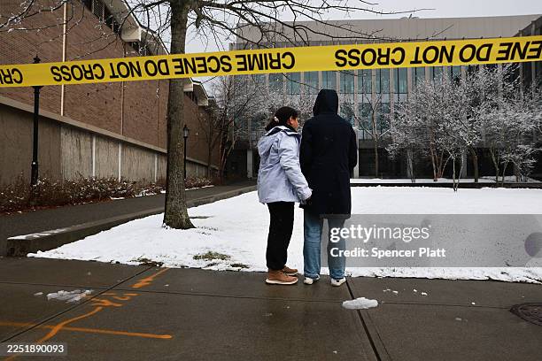 People pause outside of the engineering and physics building at Brown University, the site of a mass shooting yesterday that left at least two people...