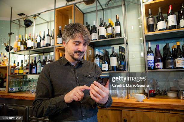 bartender stocking wine bottles in a rustic bar - bartender checking id stock pictures, royalty-free photos & images