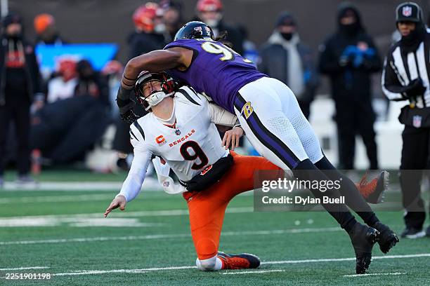 Joe Burrow of the Cincinnati Bengals throws an interception while being hit by Tavius Robinson of the Baltimore Ravens during the fourth quarter at...
