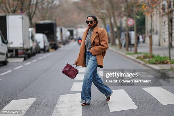 Emilie Joseph wears long straight dark brown hair parted at the center, makeup featuring an even complexion with matte skin and deep red lipstick,...