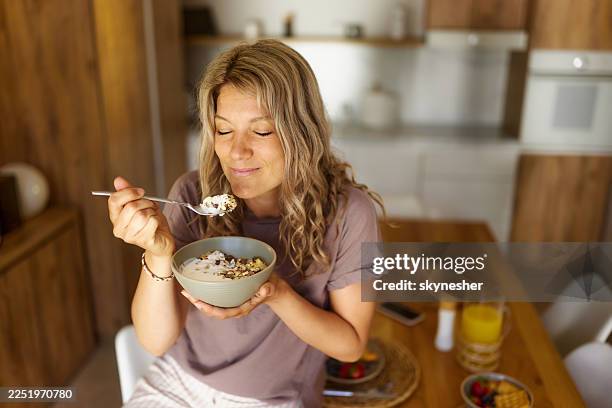 smiling woman having oatmeal for breakfast at home. - ontbijt stockfoto's en -beelden